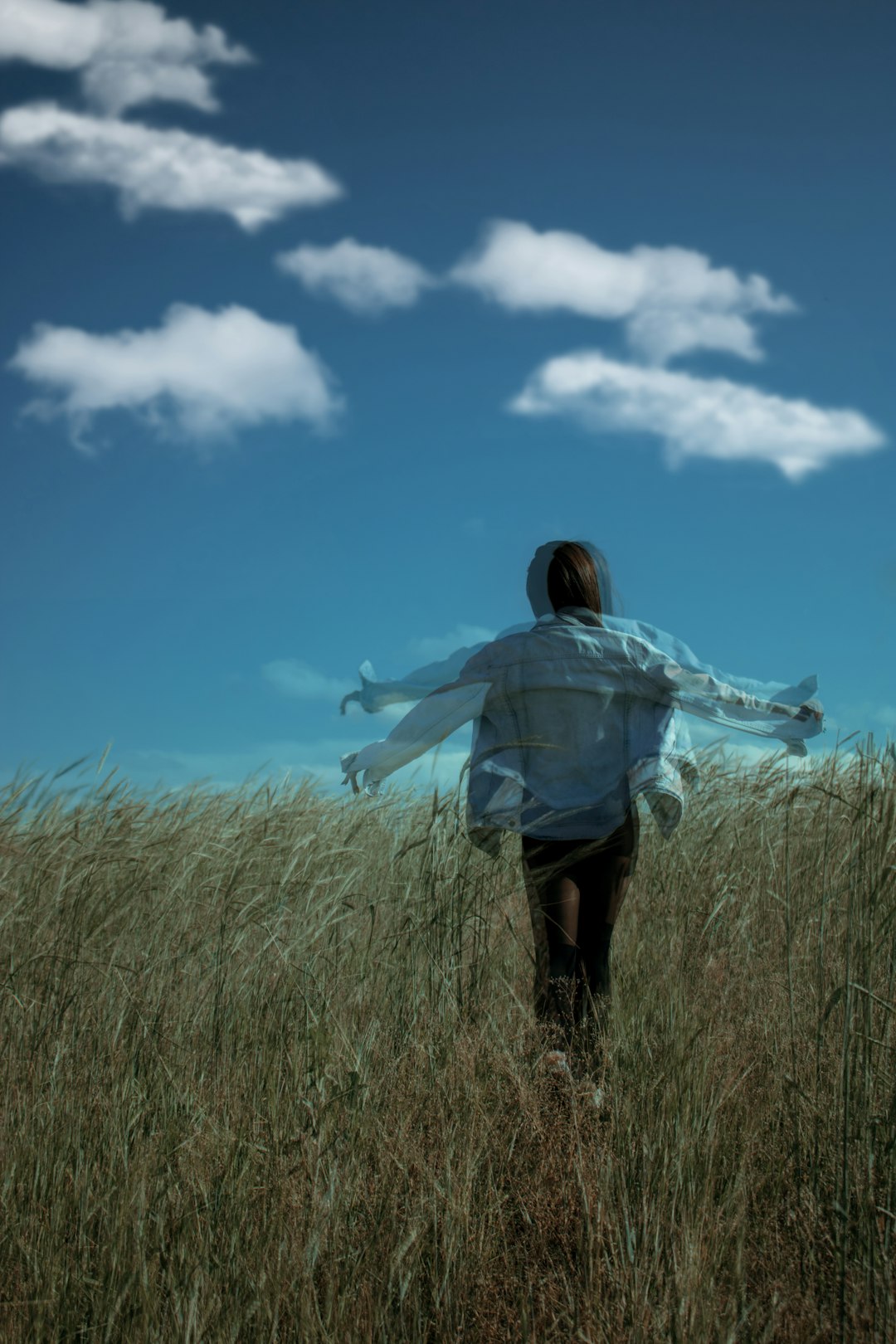 woman in white shirt and black pants standing on green grass field under blue sky and