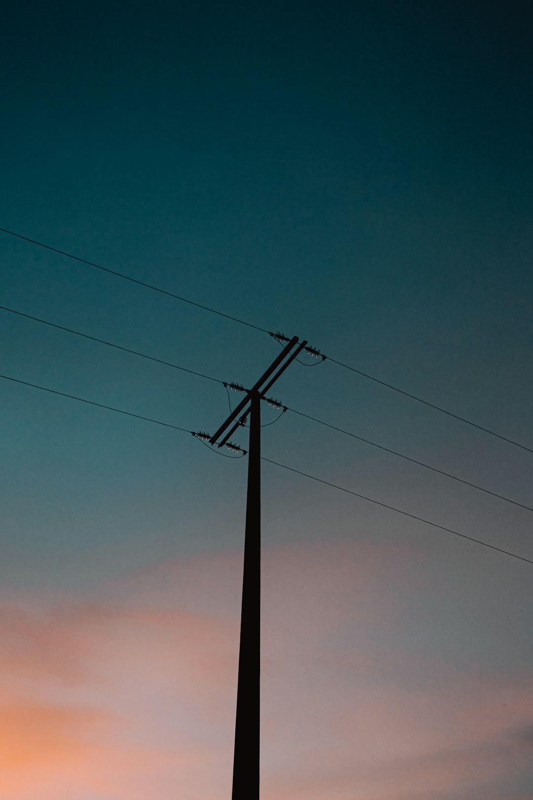 black electric post under orange sky