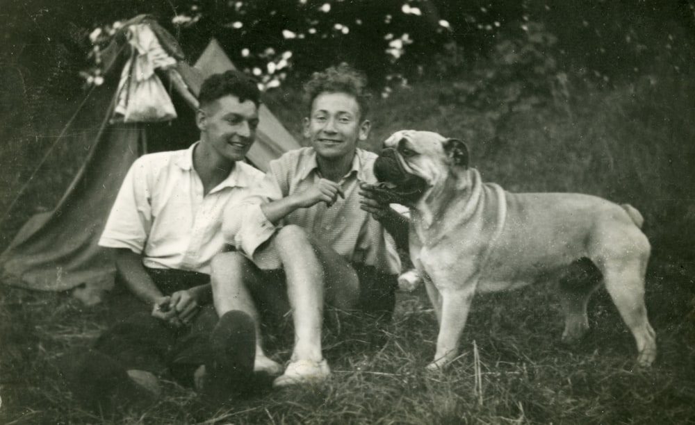 Foto en escala de grises de hombre y mujer sentados al lado del perro
