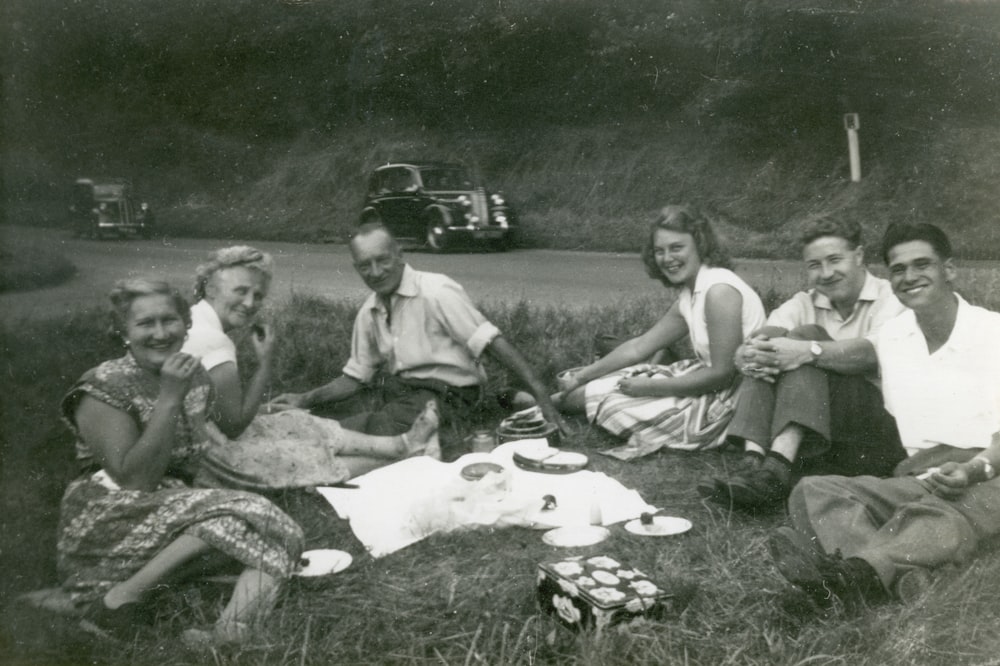 Photo en niveaux de gris de 4 hommes assis sur l’herbe