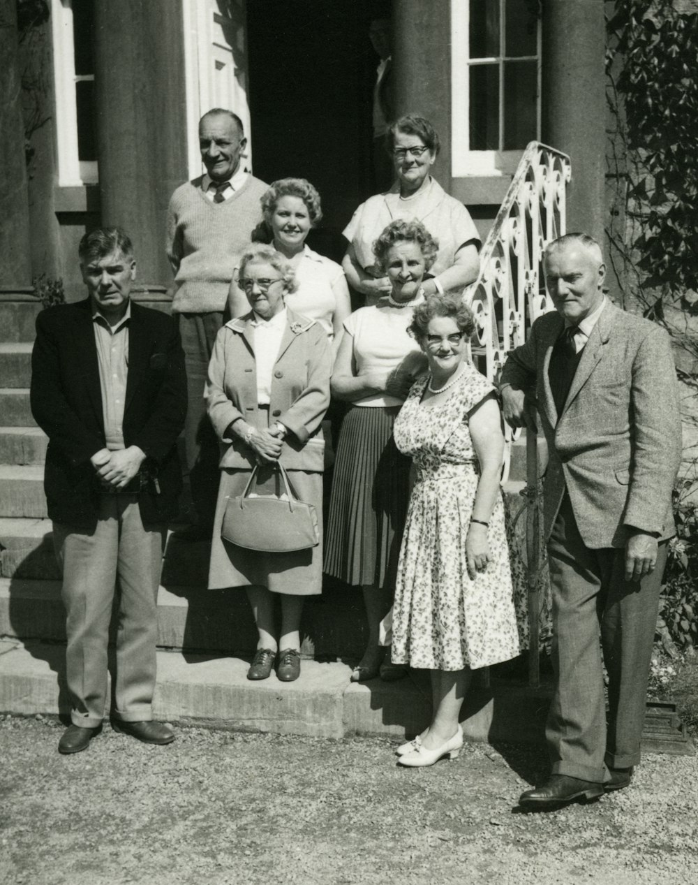 grayscale photo of family standing on grass field