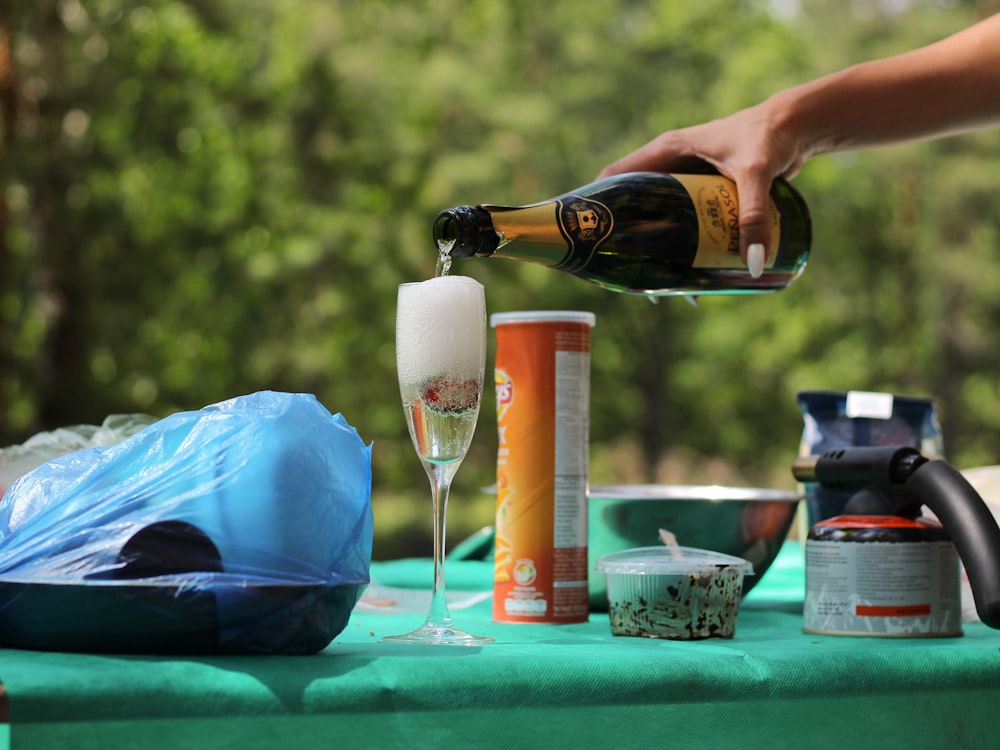 person pouring beer on beer bottle