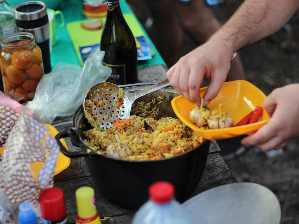 person holding yellow plastic bowl with food