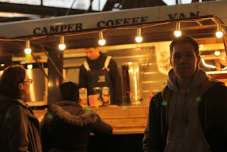 A stylish coffee trailer with a warm wooden exterior and a barista serving fresh espresso to smiling customers.