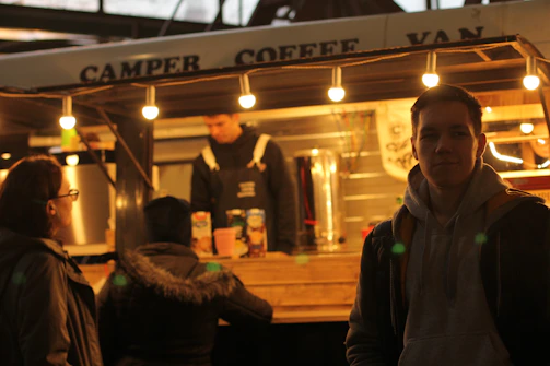 A stylish coffee trailer with a warm wooden exterior and a barista serving fresh espresso to smiling customers.
