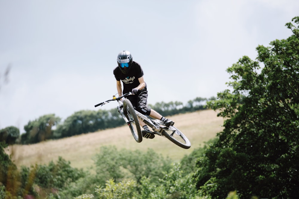 man in black shirt riding on black and white motocross dirt bike