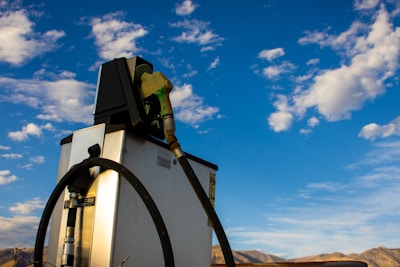 Close-up of hands holding a fuel nozzle with a clear blue sky background.