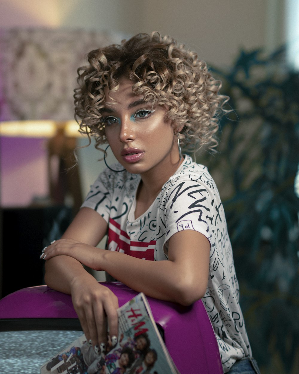 woman in white and black floral shirt sitting on pink chair