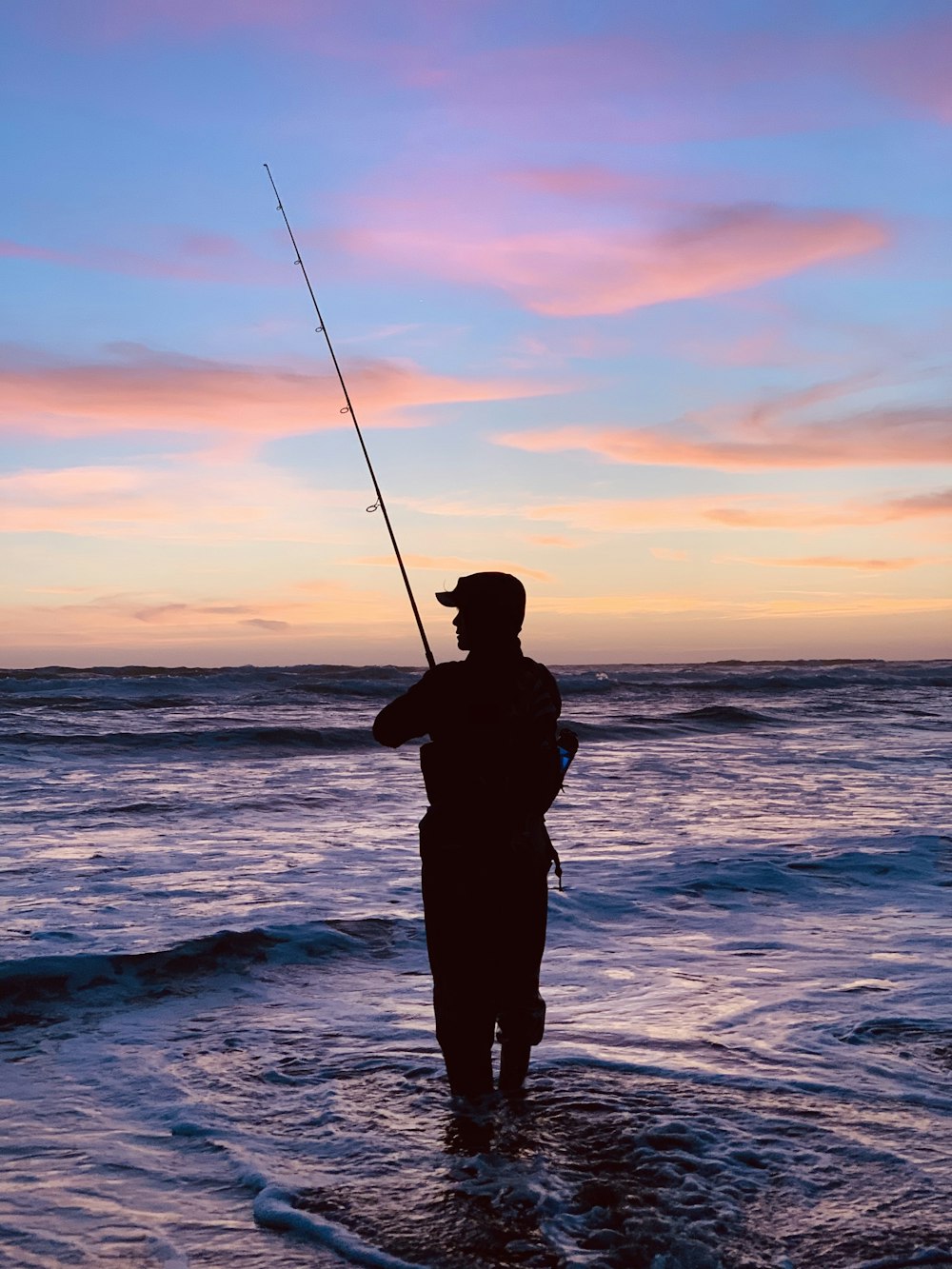 Silueta del hombre pescando durante la puesta del sol