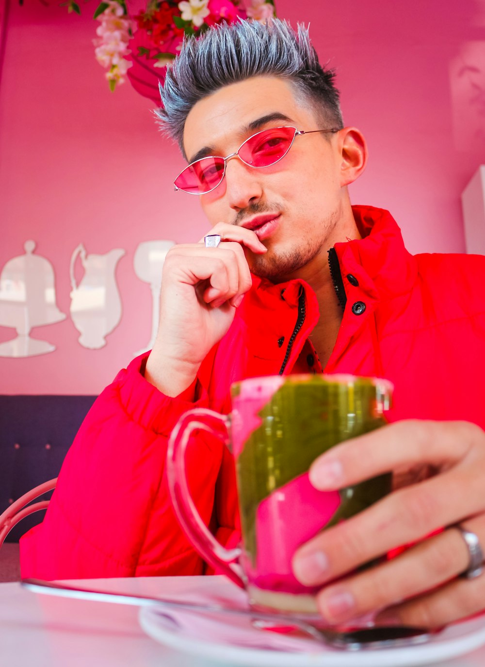 緑のガラスのマグカップから飲む赤いジャケットの男