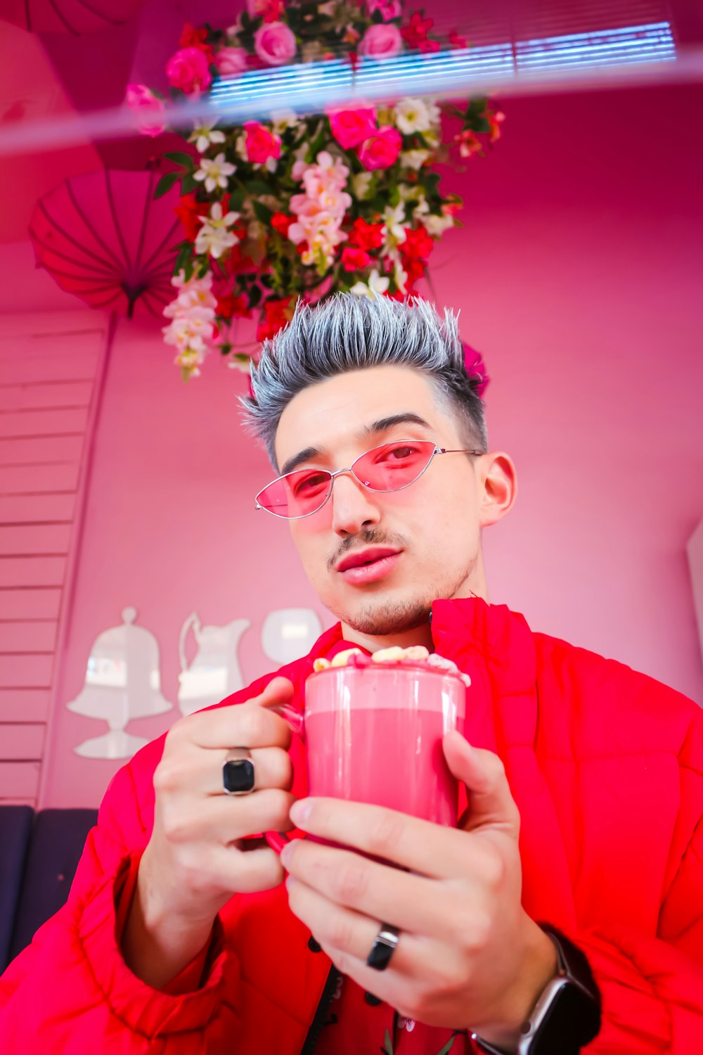 man in red sweater holding pink and white ceramic mug