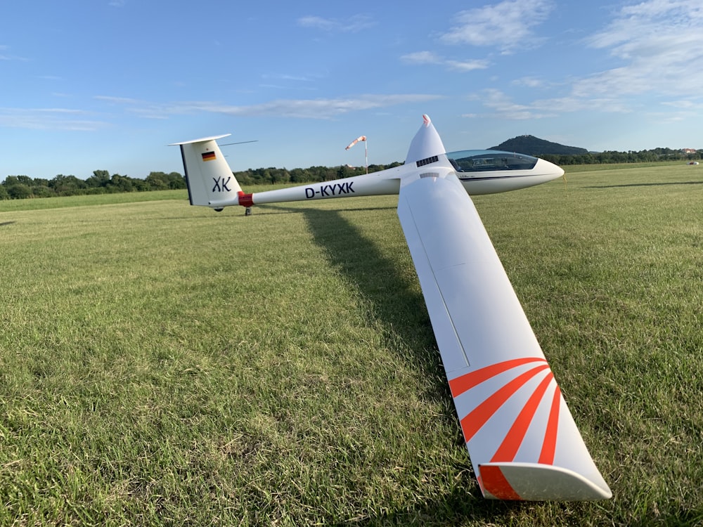 weiß-rotes Flugzeug tagsüber auf grünem Rasen