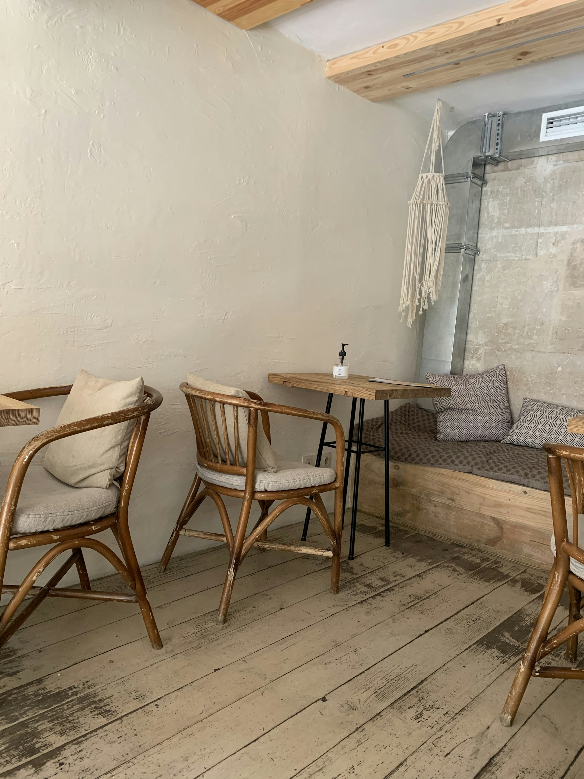 Cozy corner seating at Vertigo Cafe with rustic wooden tables, soft cushions, and hanging plants creating an inviting atmosphere.