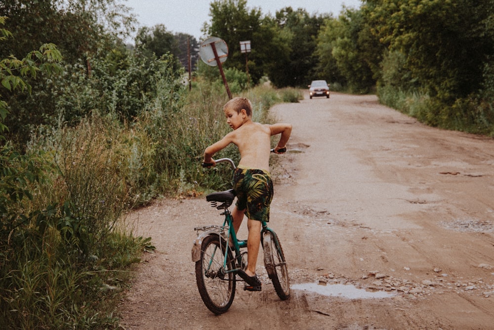 boy in green shorts riding on bicycle during daytime