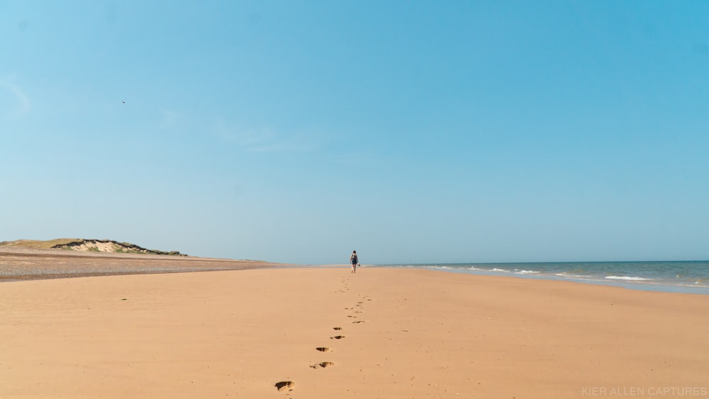 persona che cammina sulla spiaggia durante il giorno