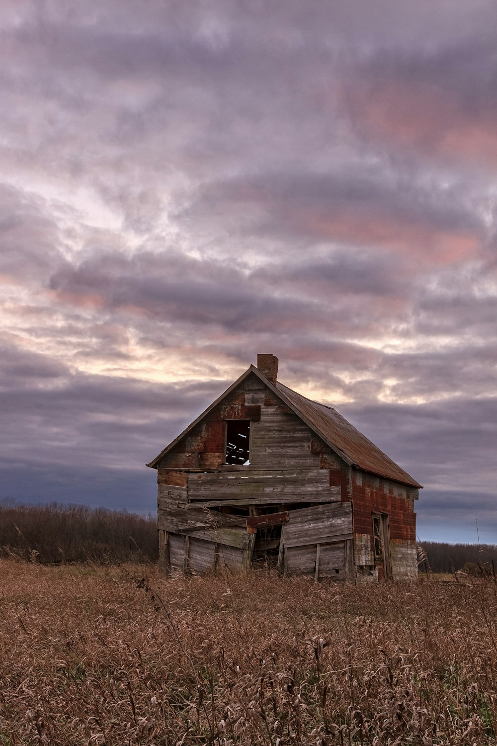 brown wooden barn on brown grass field under gray clouds