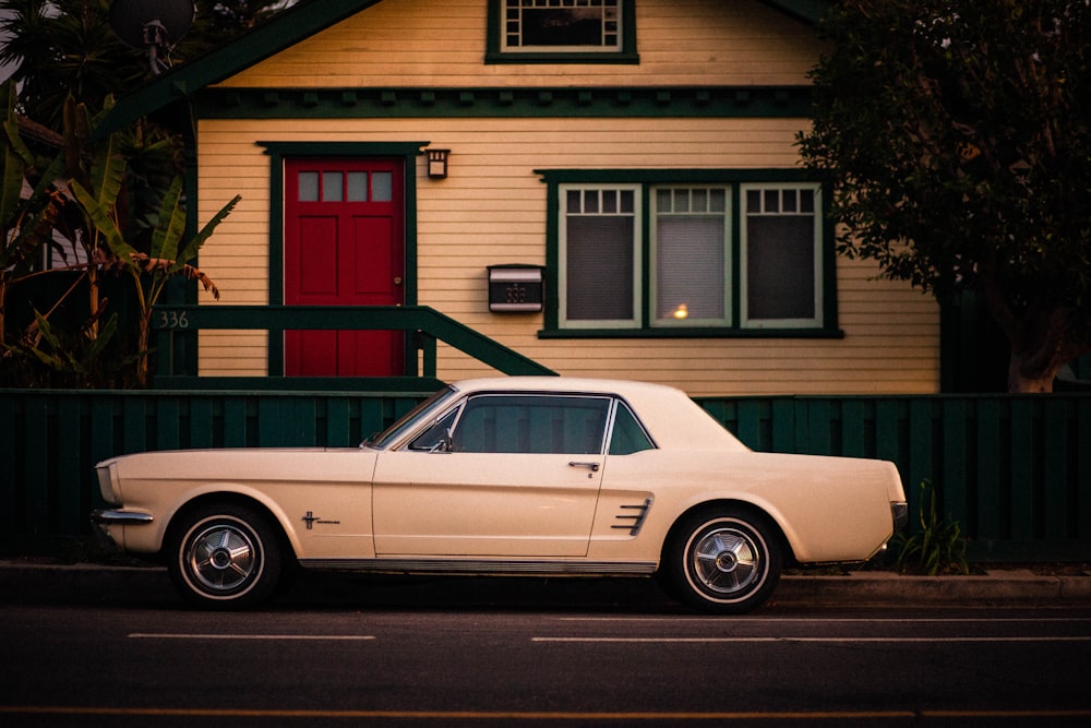 white coupe parked in front of white and red house