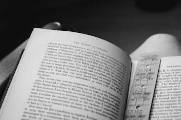 An open book showcasing a page titled 'The Ascent of Everest' with text in English. A vintage-style transport service ticket is used as a bookmark. The image is in black and white, emphasizing the contrast between the text and the page.