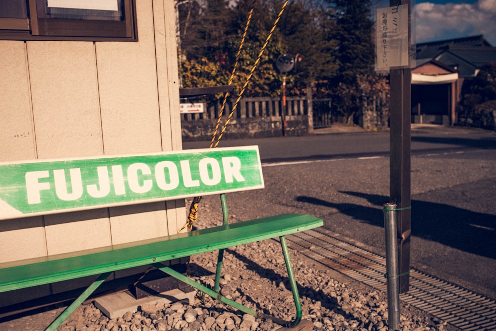 a green bench sitting in front of a building