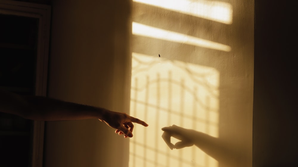 persons hand on white window curtain