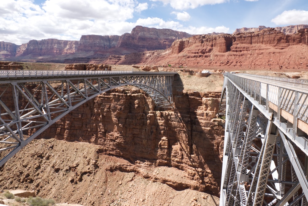 white metal bridge over brown rocky mountain during daytime