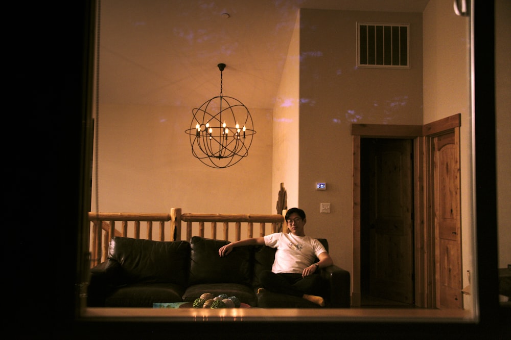 man in white dress shirt sitting on black couch