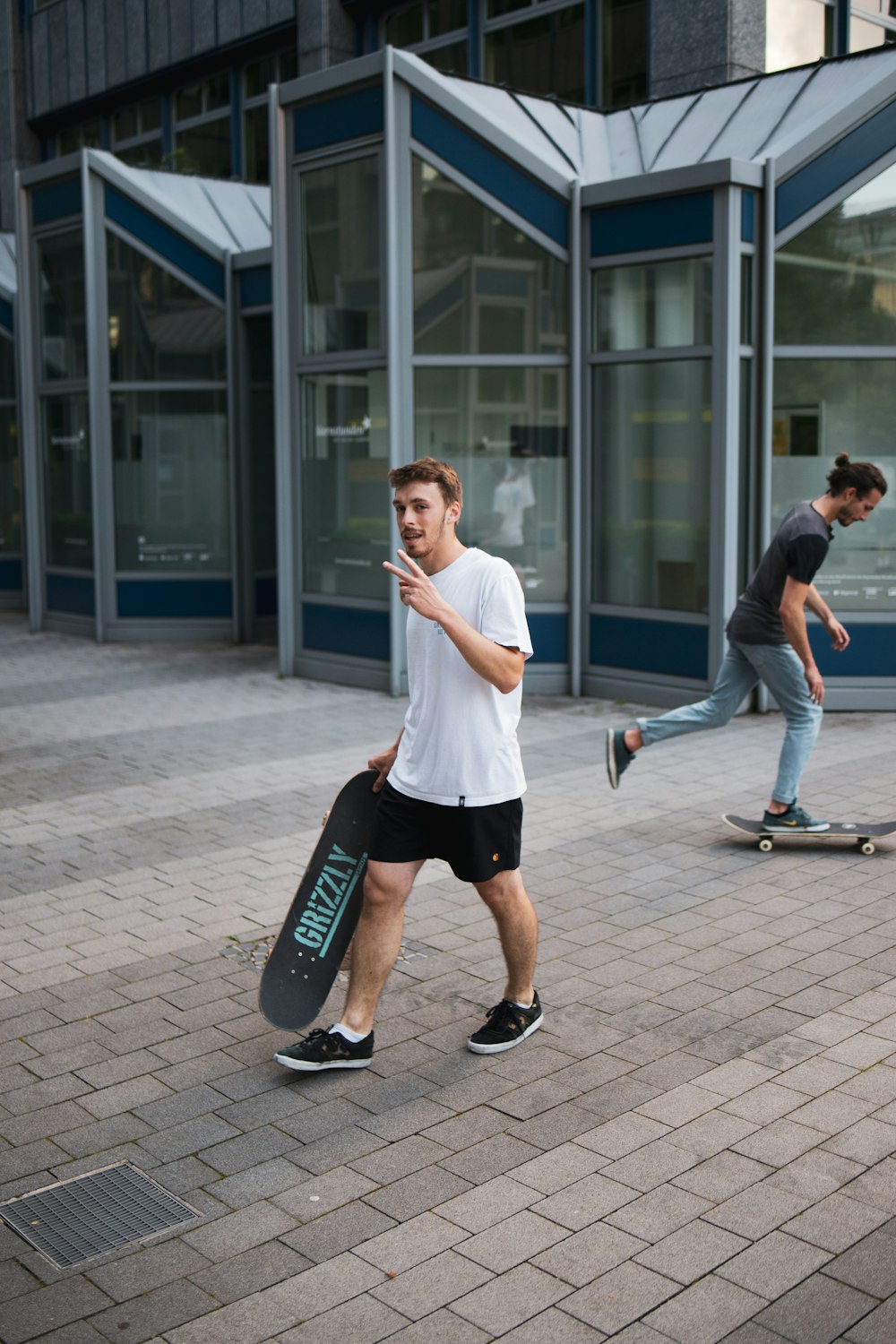 白いTシャツと黒い短パンを着た男性が昼間、スケートボードをしている