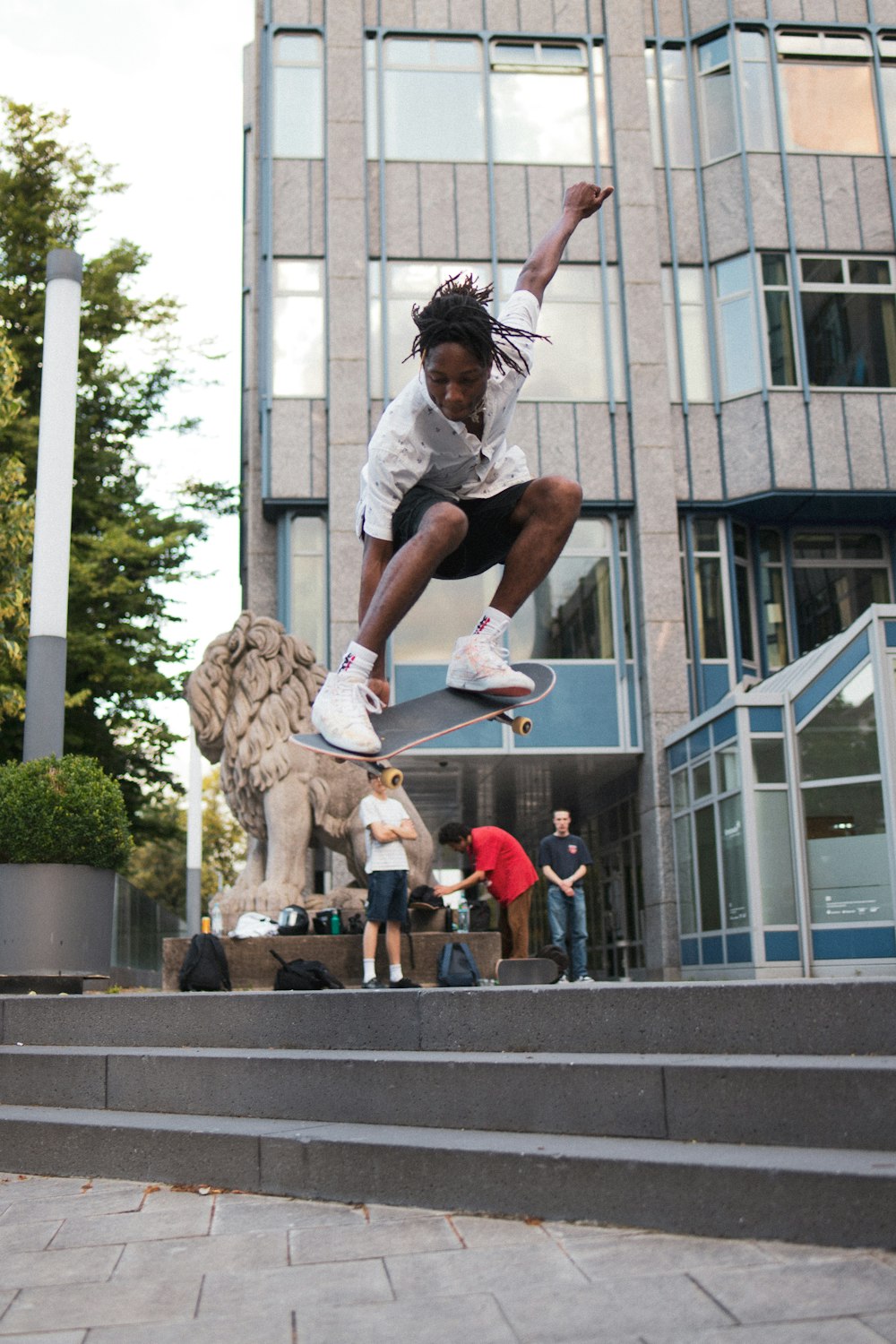 woman in white t-shirt and black shorts jumping on water fountain during daytime