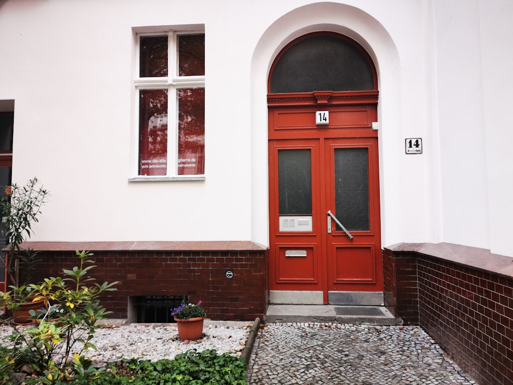 red wooden door on white concrete house