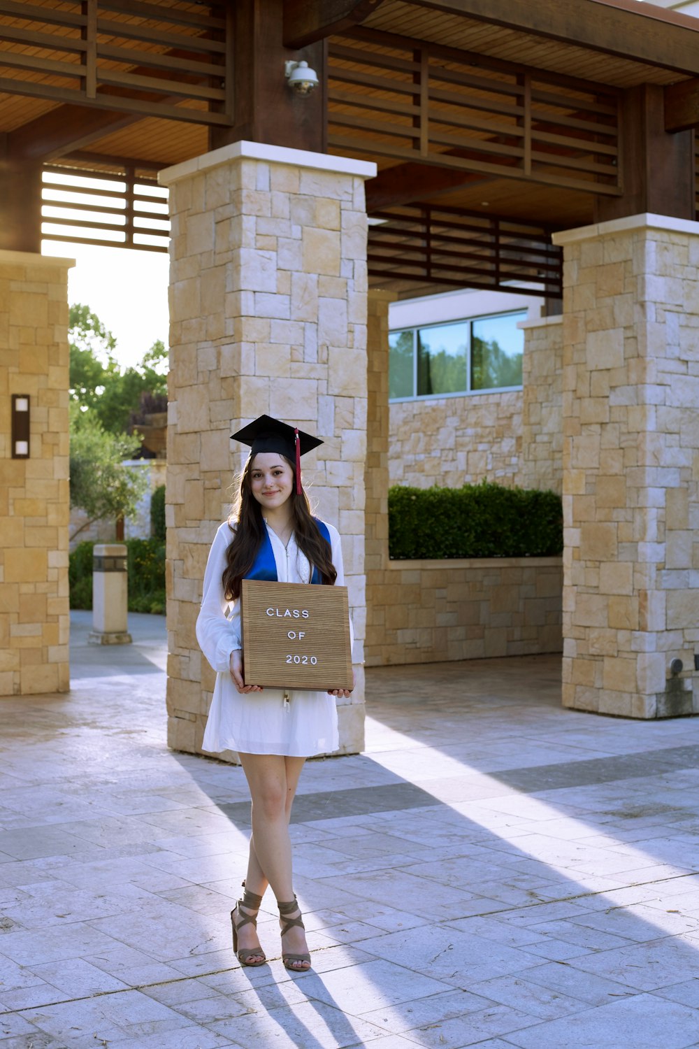 Mujer en vestido académico sosteniendo una bolsa de papel marrón