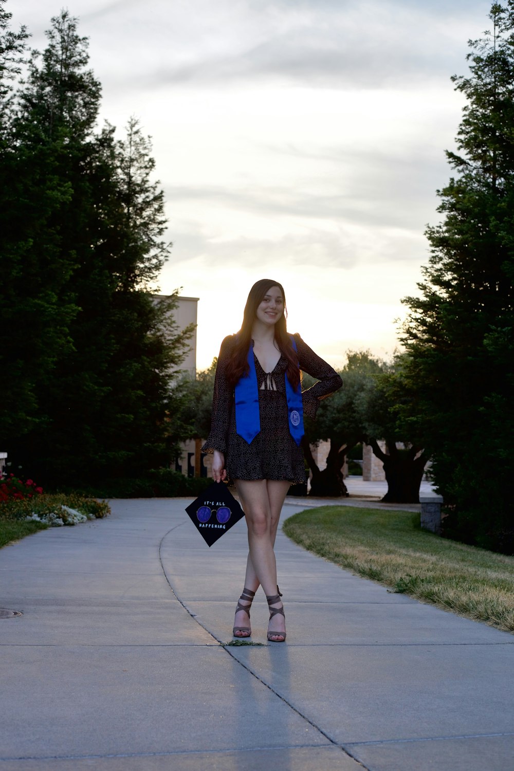 woman in blue long sleeve dress standing on gray concrete pathway