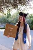 woman in blue academic gown holding brown wooden board