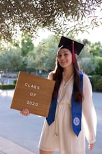woman in blue academic gown holding brown wooden board