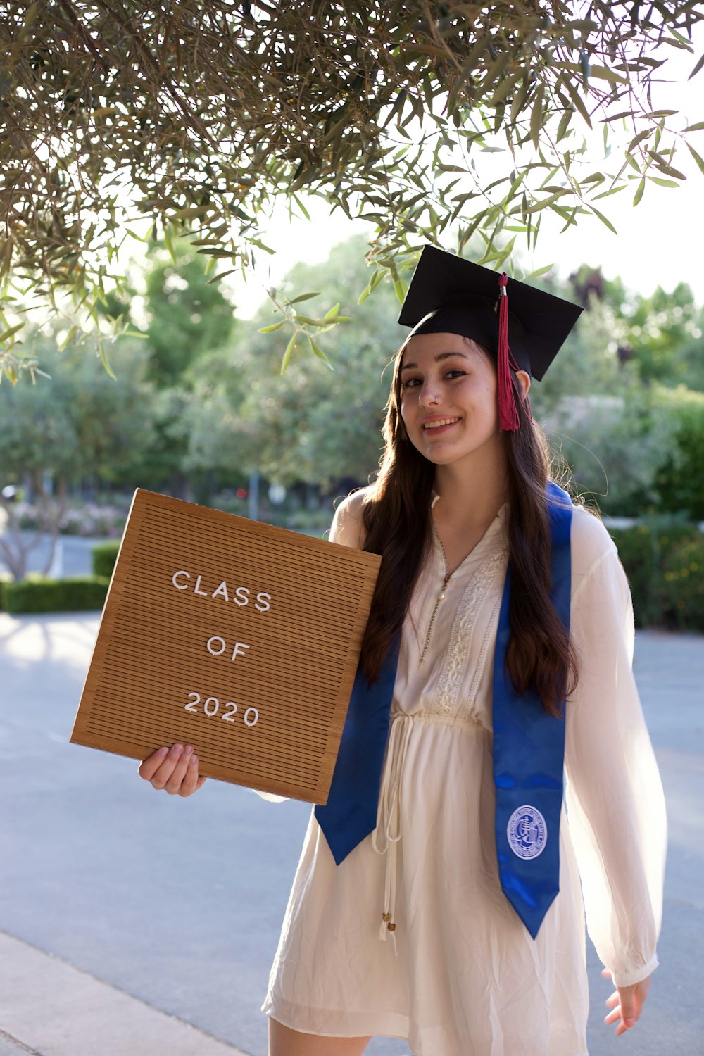 woman in blue academic gown holding brown wooden board