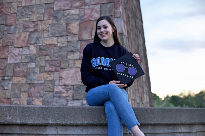 Smiling woman holding a graduation cap, symbolizing successful completion of a Master's in AIprogram