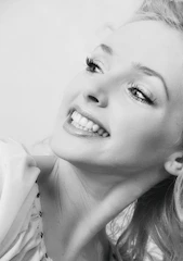 Portrait of a joyful Black mother smiling softly in a warm, beige-toned room.