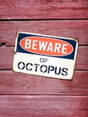 a beware of octopus sign on a wooden wall