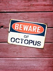 a beware of octopus sign on a wooden wall