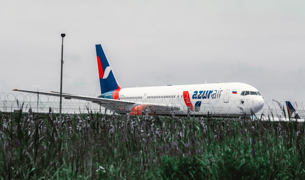 white and red passenger plane on green grass field