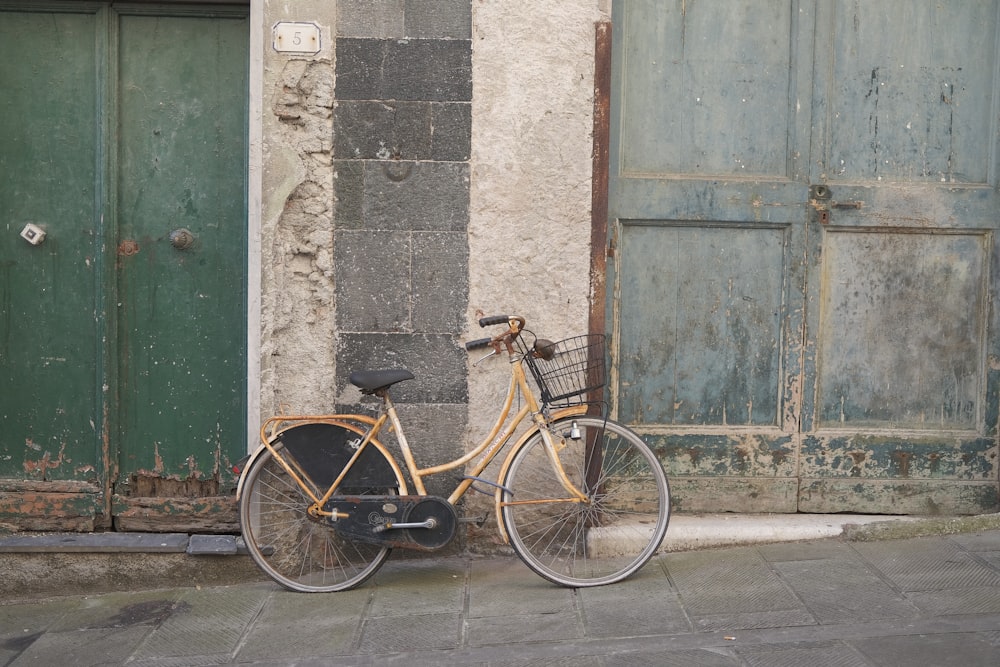 brown city bike parked beside green wooden door