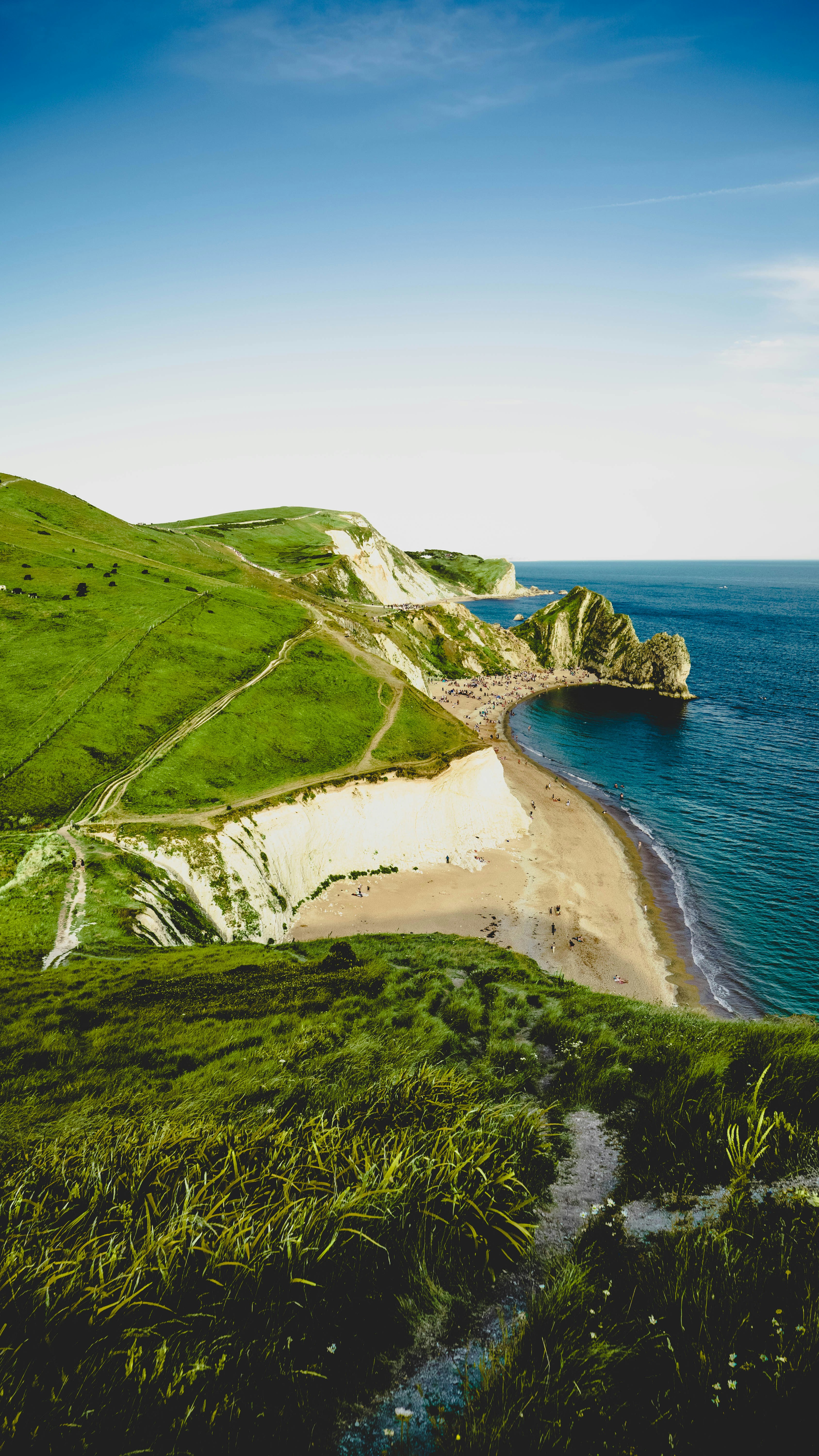 green and brown mountain beside blue sea under white sky during daytime