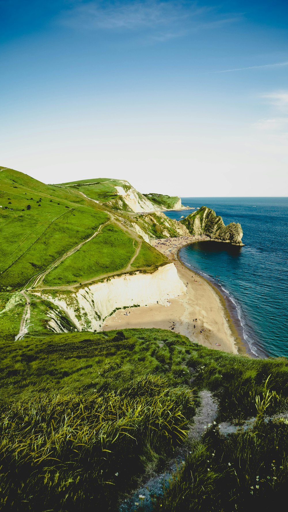 green and brown mountain beside blue sea under white sky during daytime