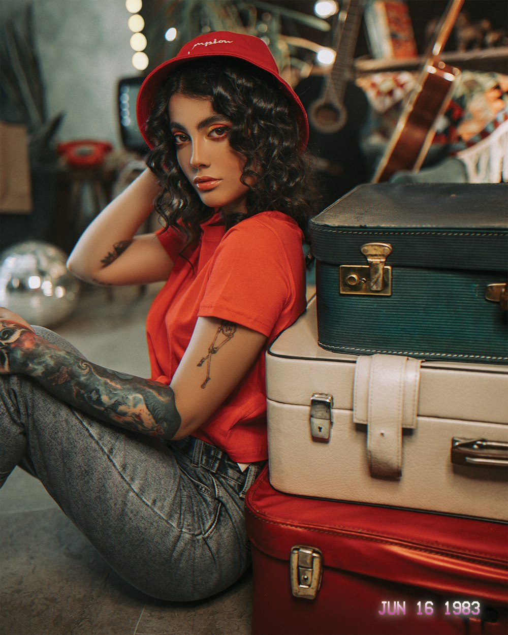 woman in red shirt and blue denim jeans sitting on brown suitcase