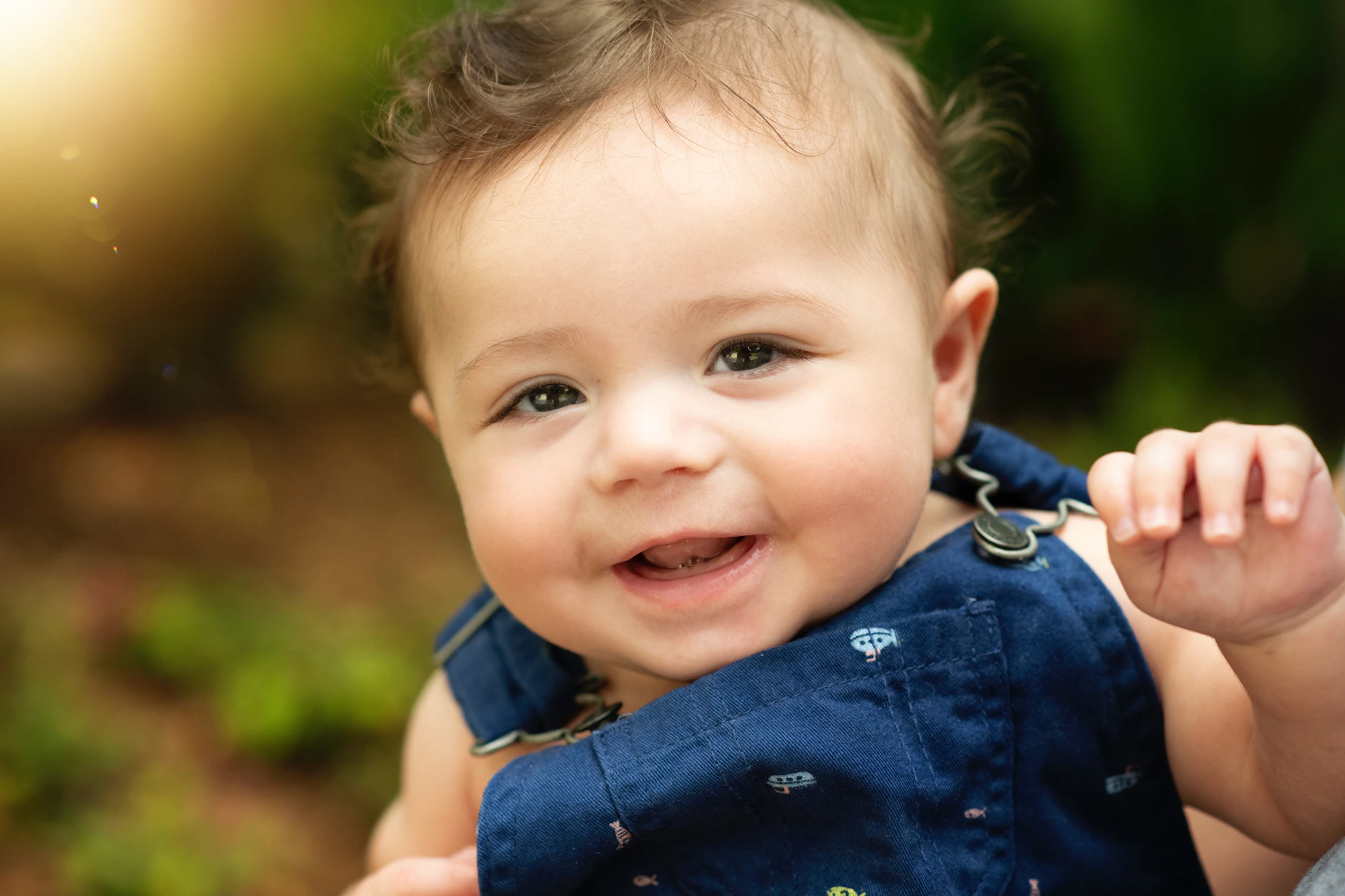 A soft pastel-toned photo of baby Riya Sanvi giggling with tiny sparkles and floating hearts around her.