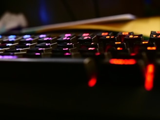 A close-up shot of a mechanical keyboard with ambient blue and purple lighting reflecting on the keys.