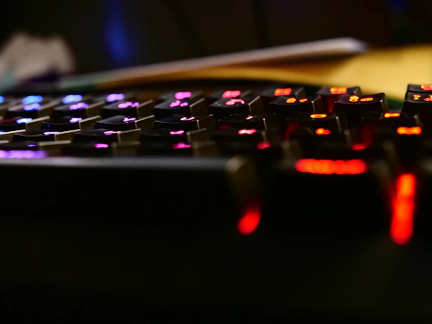 Close-up of a gamer’s hands on a glowing mechanical keyboard with purple and blue neon lights