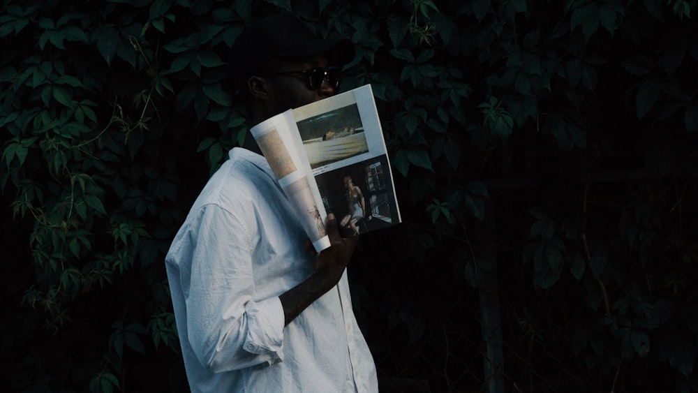 man in white dress shirt holding book