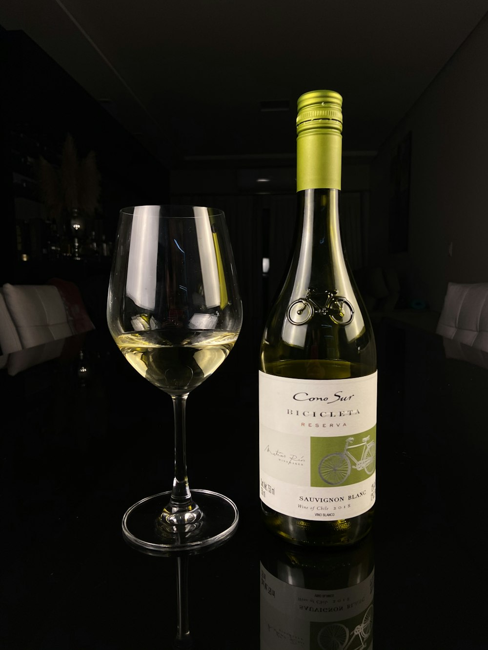 white labeled bottle beside wine glass