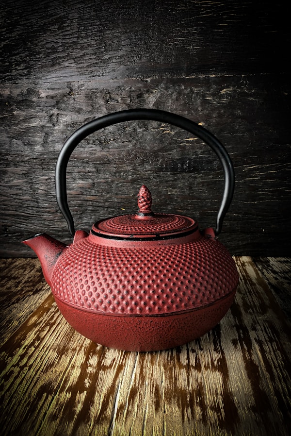 red ceramic teapot on brown wooden table