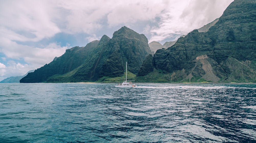 white boat on sea near mountain during daytime